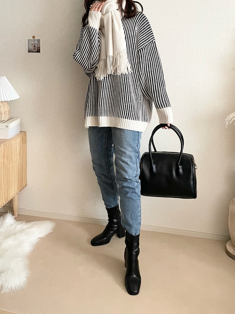 ブラック系のニット/セーター、ブルー系のデニムパンツ、ブラック系のボストンバッグを着用したレディースの冬コーディネートの1枚目の写真