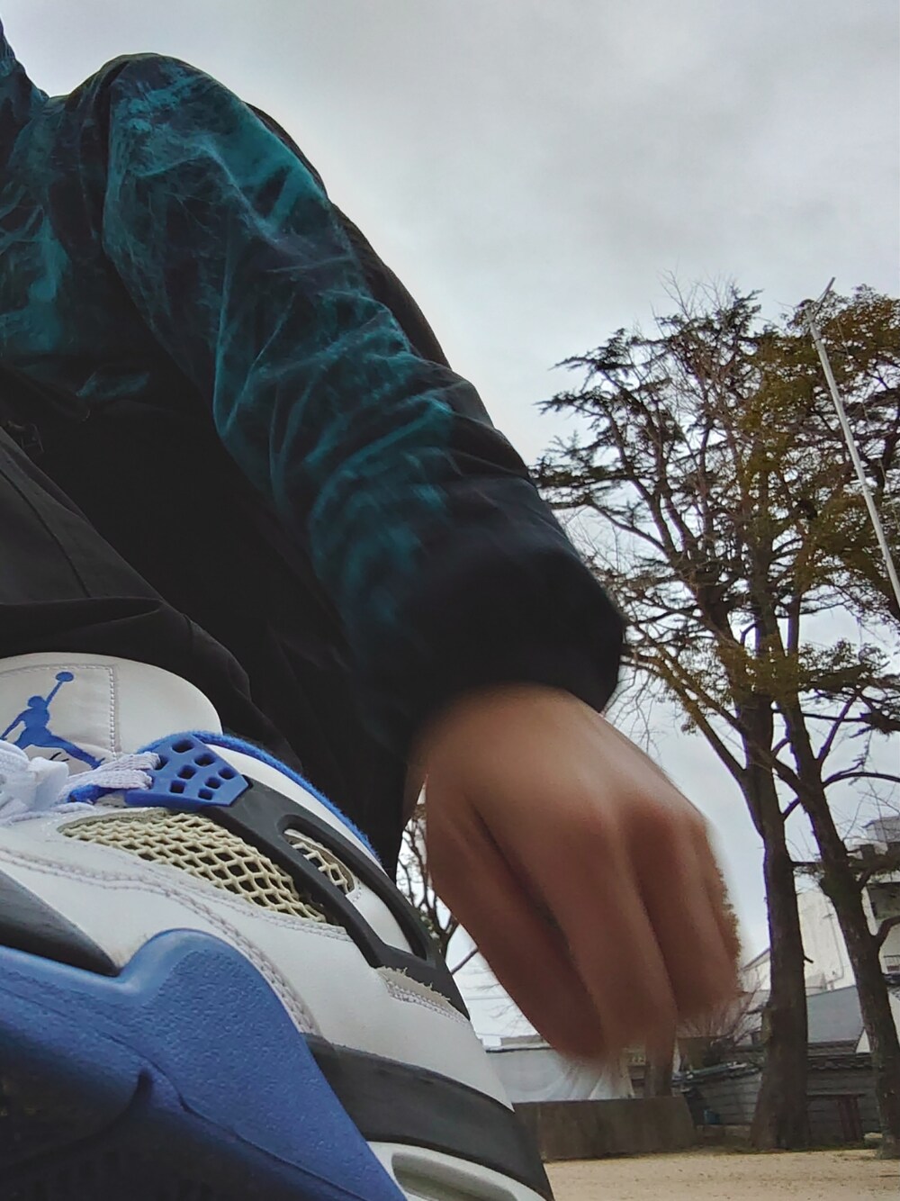 ブルー系のナイロンジャケット、ホワイト系のスニーカー、ブラック系のカーゴパンツを着用したメンズの春コーディネートの1枚目の写真