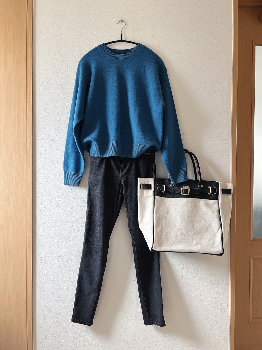 ブルー系のニット/セーター、ブラック系のデニムパンツ、ブラック系のトートバッグを着用したレディースの秋コーディネートの1枚目の写真