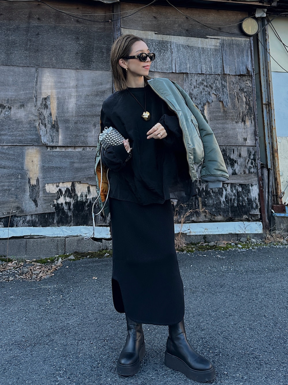 グリーン系のMA-1、シルバー系のバッグ、ブラック系のブーツを着用したレディースの冬コーディネートの1枚目の写真