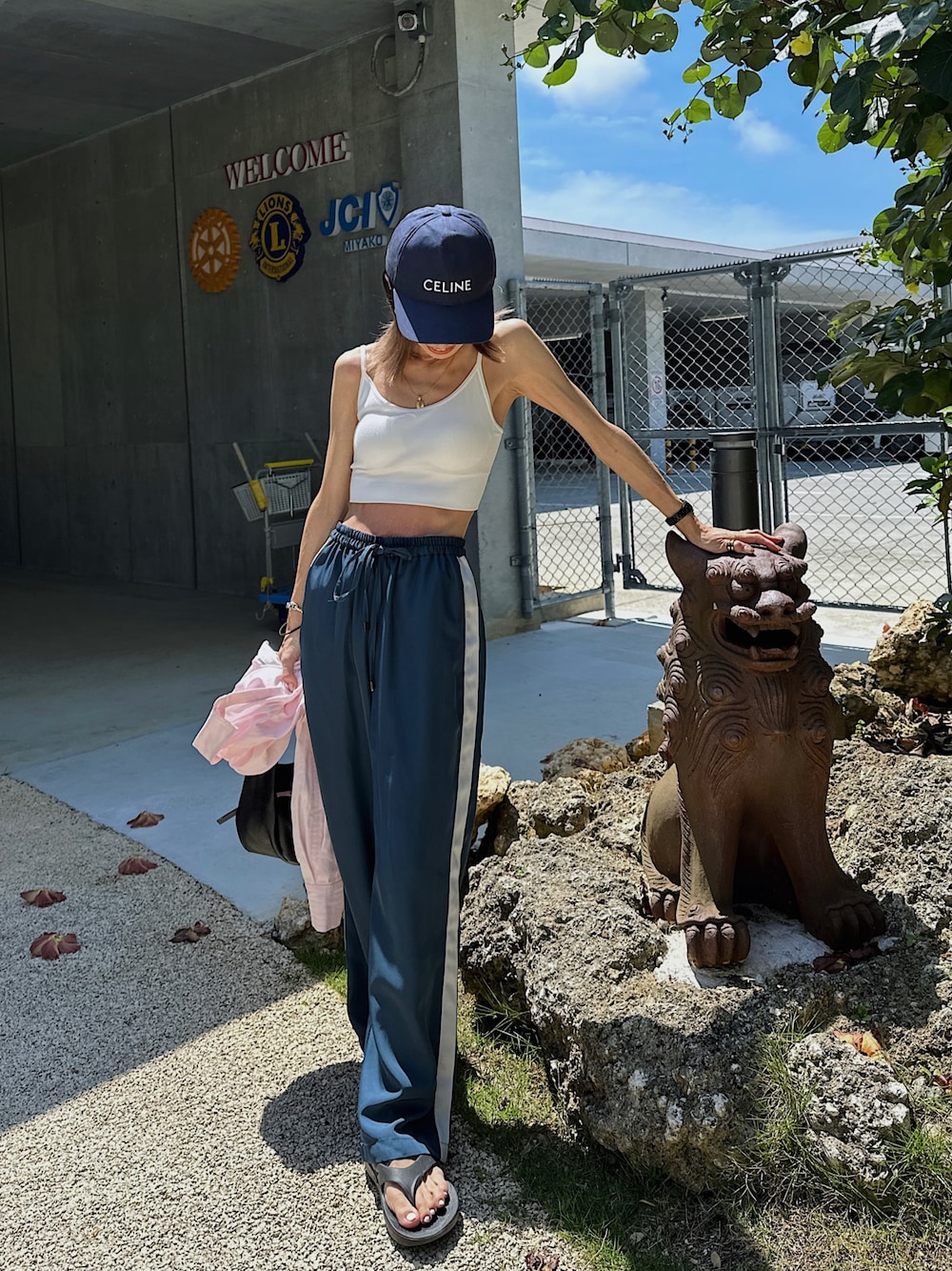 ブルー系のパンツ、ブラック系のサンダル、ブラック系のハンドバッグを着用したレディースの夏コーディネートの1枚目の写真