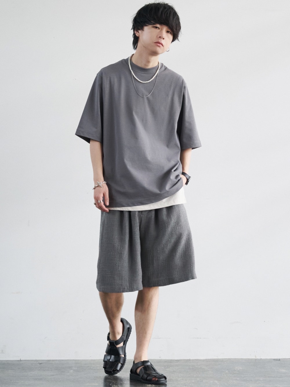 グレー系のTシャツ/カットソー、ホワイト系のタンクトップ、グレー系のスラックスを着用したメンズの夏コーディネートの1枚目の写真