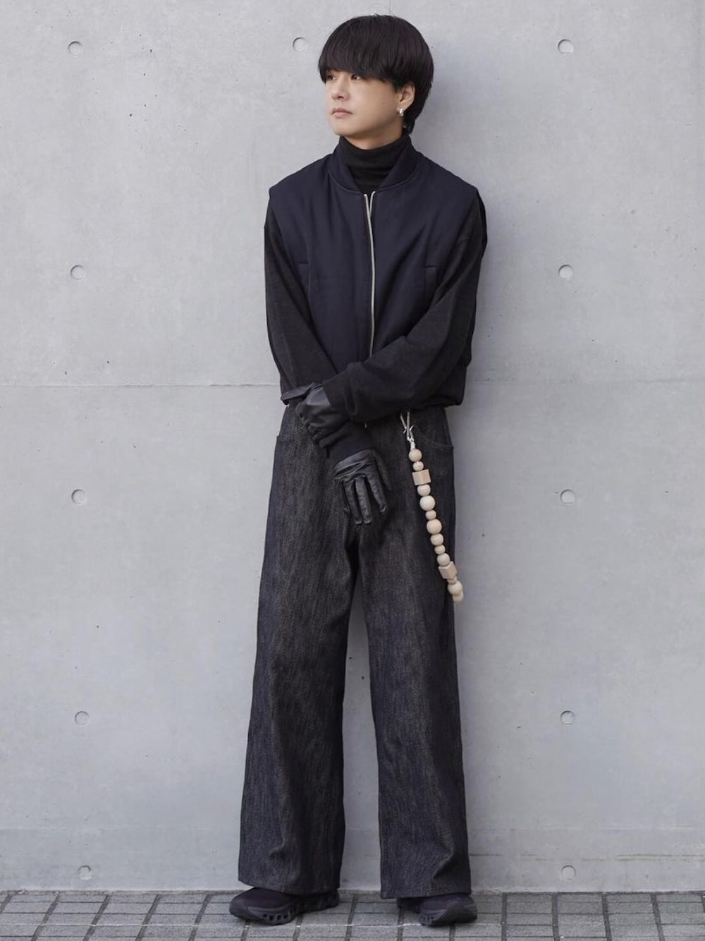 ブラック系のベスト、グレー系のニット/セーター、ブラック系のデニムパンツを着用したメンズの冬コーディネートの1枚目の写真