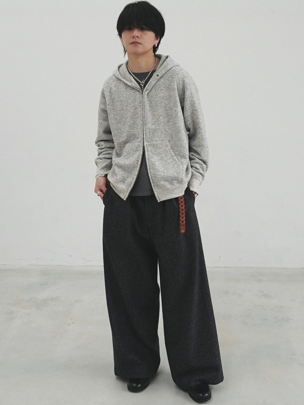 グレー系のパーカー、グレー系のTシャツ/カットソー、ブラック系のスラックスを着用したメンズの冬コーディネートの1枚目の写真