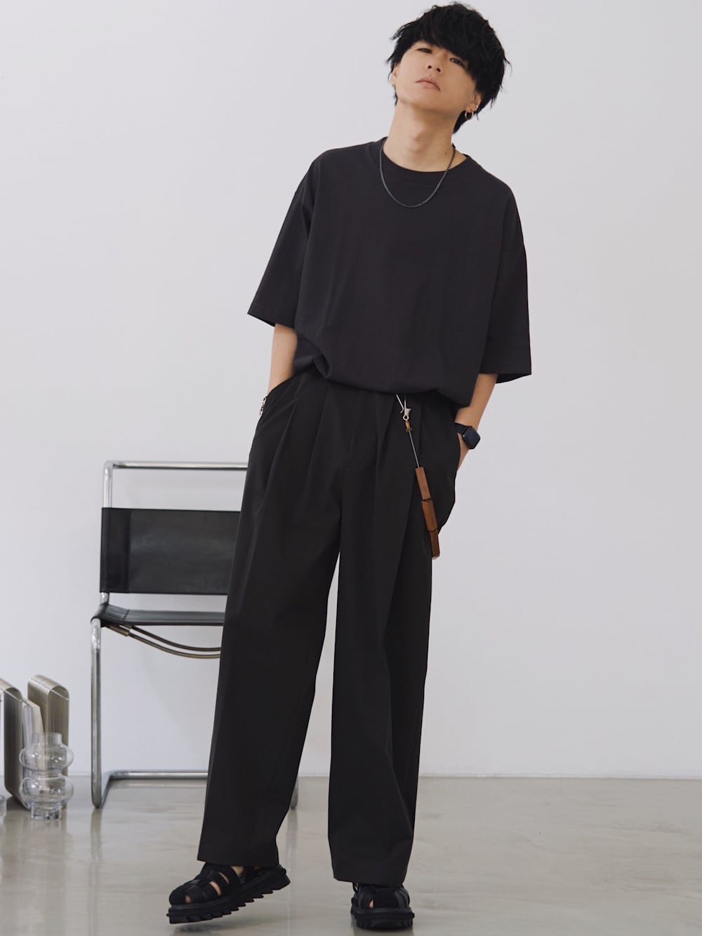 グレー系のTシャツ/カットソー、グレー系のスラックス、ブラック系のサンダルを着用したメンズの春コーディネートの1枚目の写真