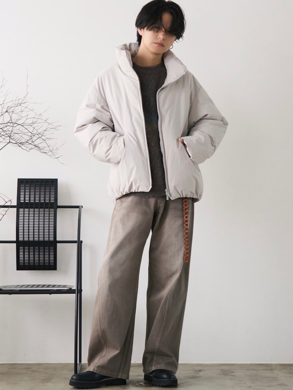 グレー系のダウンジャケット/コート、グリーン系のニット/セーター、ブラウン系のデニムパンツを着用したメンズの秋コーディネートの1枚目の写真