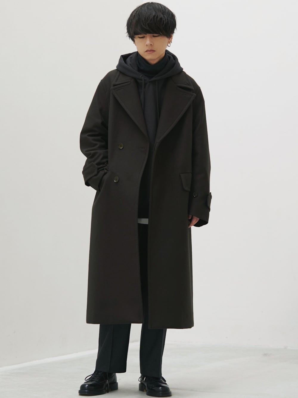 グリーン系のチェスターコート、グレー系のパーカー、ホワイト系のタンクトップを着用したメンズの秋コーディネートの1枚目の写真