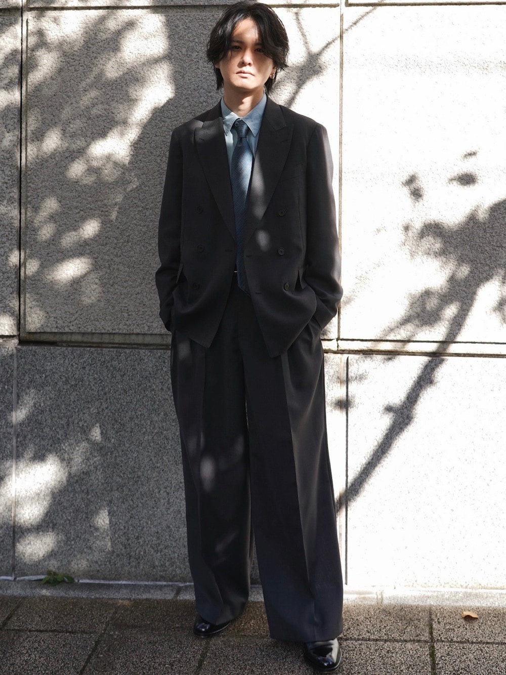 グレー系のテーラードジャケット、グレー系のスラックス、シルバー系のピアス(両耳用)を着用したメンズの冬コーディネートの1枚目の写真