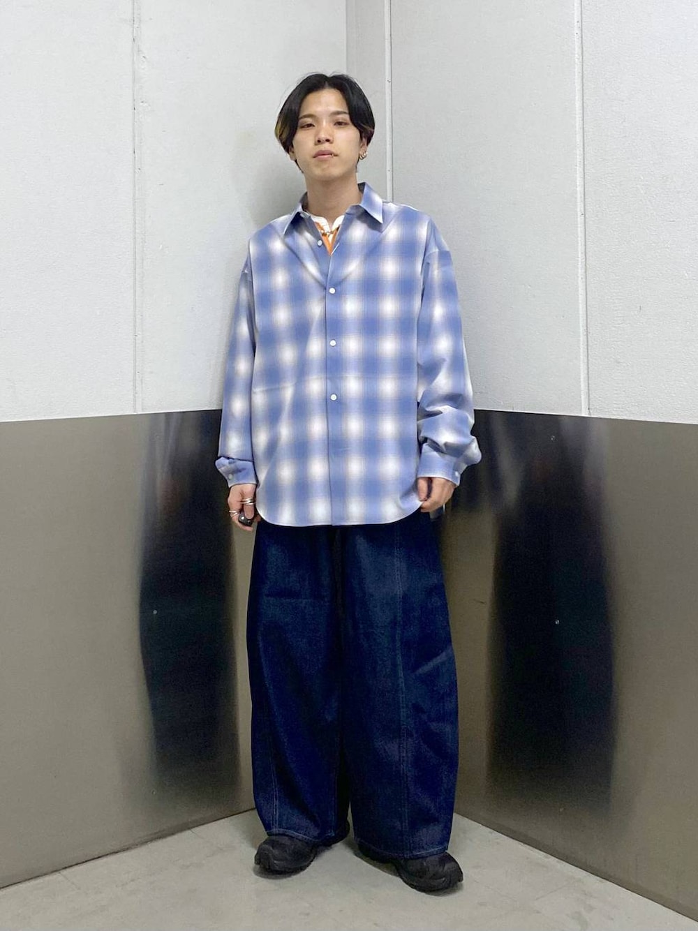 ブラック系のスニーカー、ブルー系のシャツ/ブラウス、オレンジ系のTシャツ/カットソーを着用したメンズの春コーディネートの1枚目の写真