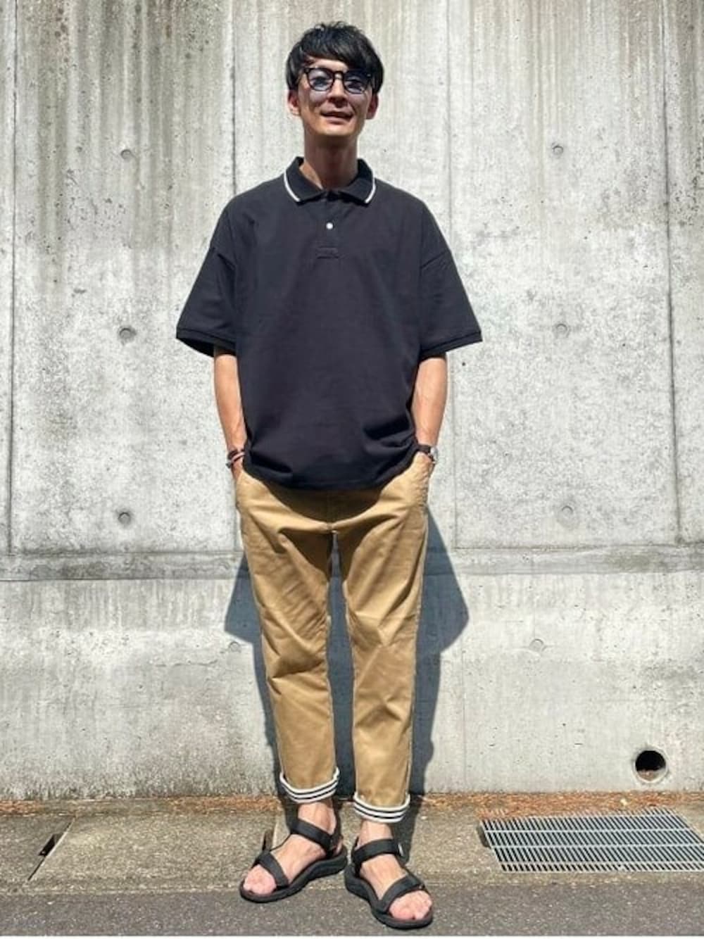 ブラック系のポロシャツ、ベージュ系のその他パンツ、ブラック系のサンダルを着用したメンズの夏コーディネートの1枚目の写真