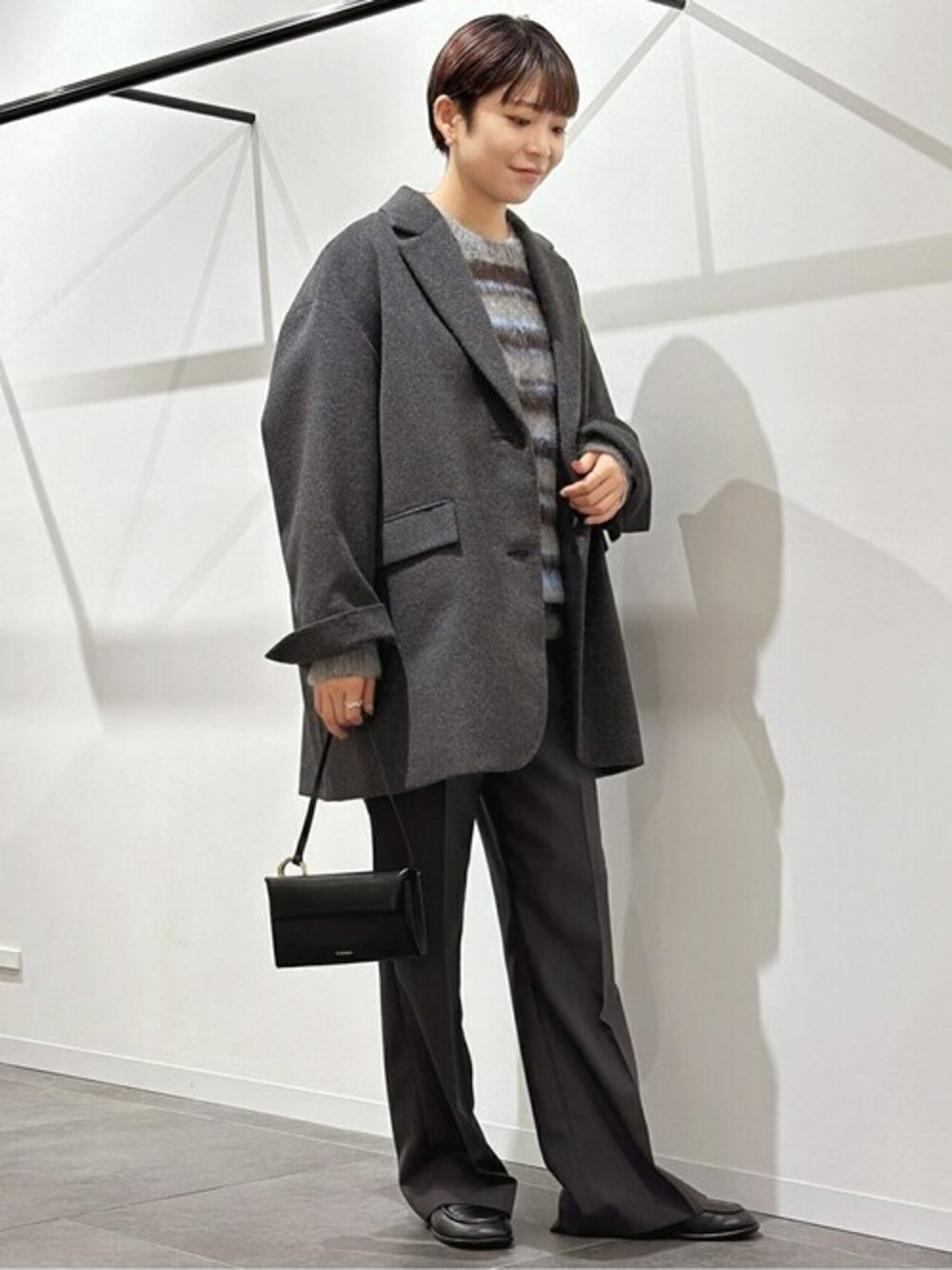 グレー系のその他アウター、グレー系のニット/セーター、ブラック系のローファーを着用したレディースの秋コーディネートの1枚目の写真