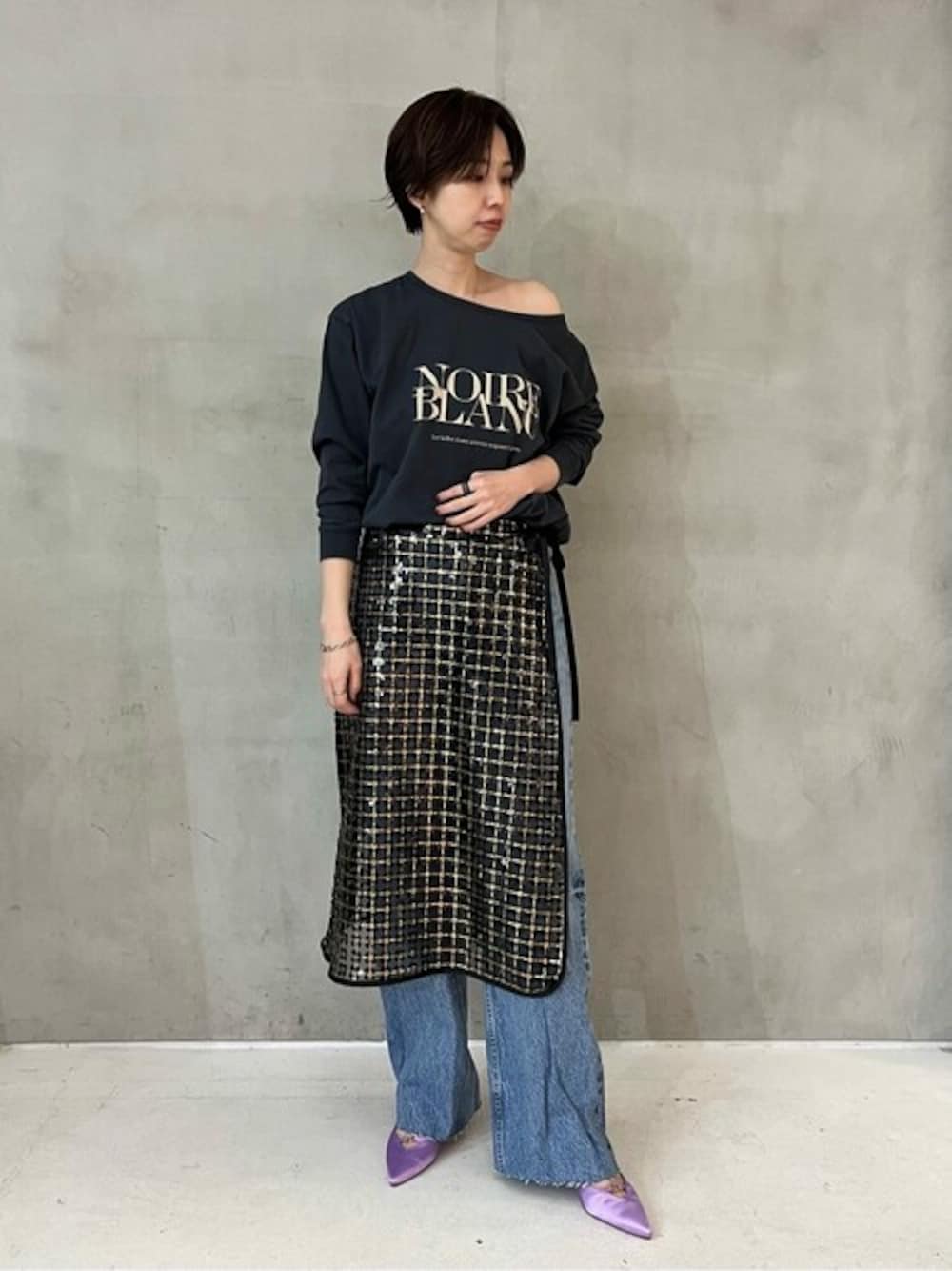 パープル系のパンプス、ブラック系のスカートを着用したレディースの春コーディネートの1枚目の写真