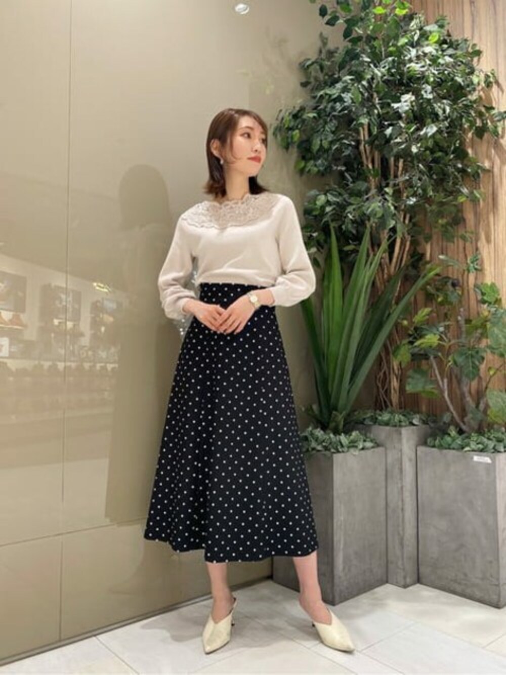 ホワイト系のニット/セーター、ブラック系のスカートを着用したレディースの春コーディネートの1枚目の写真