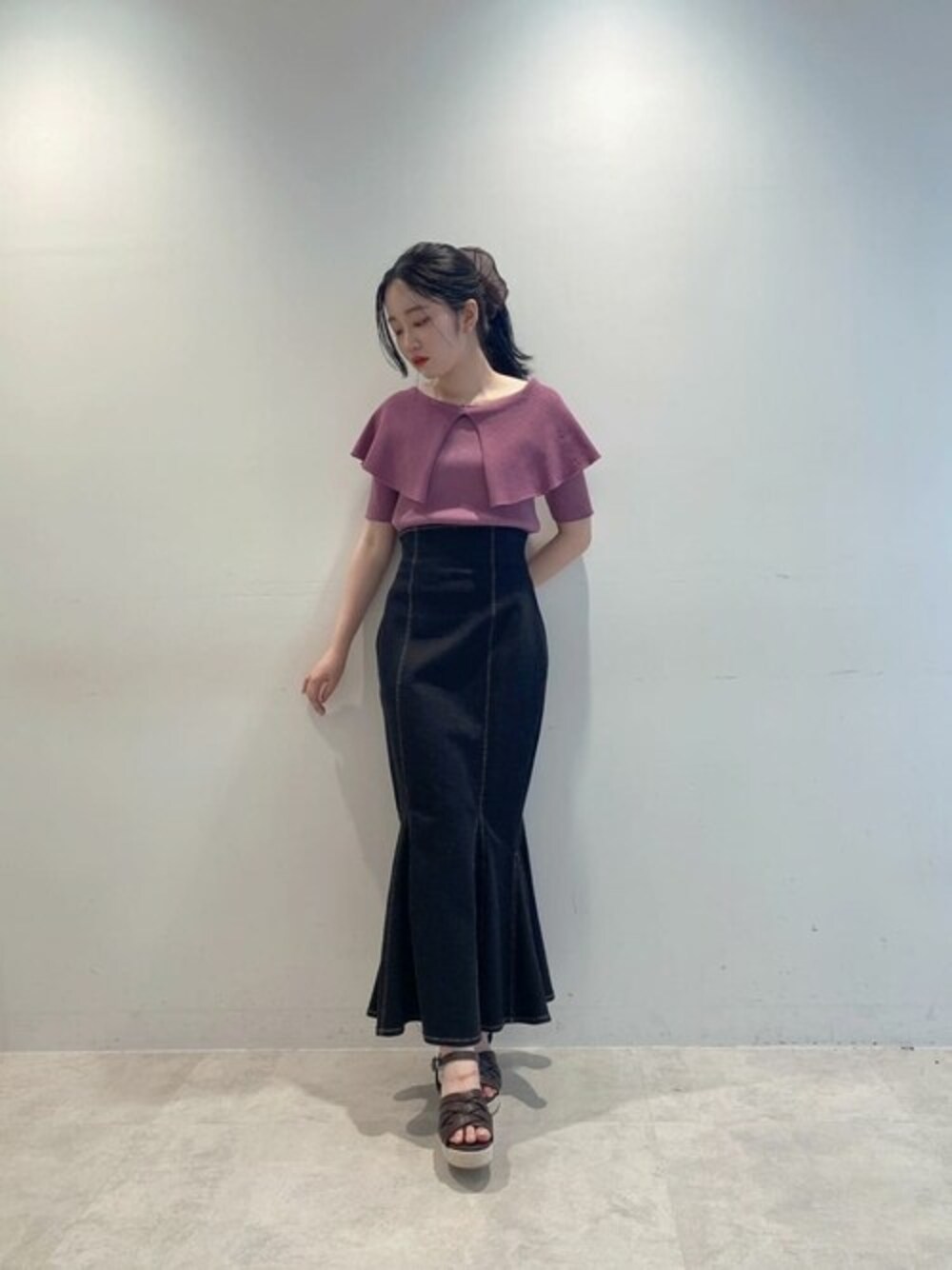 ピンク系のニット/セーター、ブラック系のスカートを着用したレディースの春コーディネートの1枚目の写真