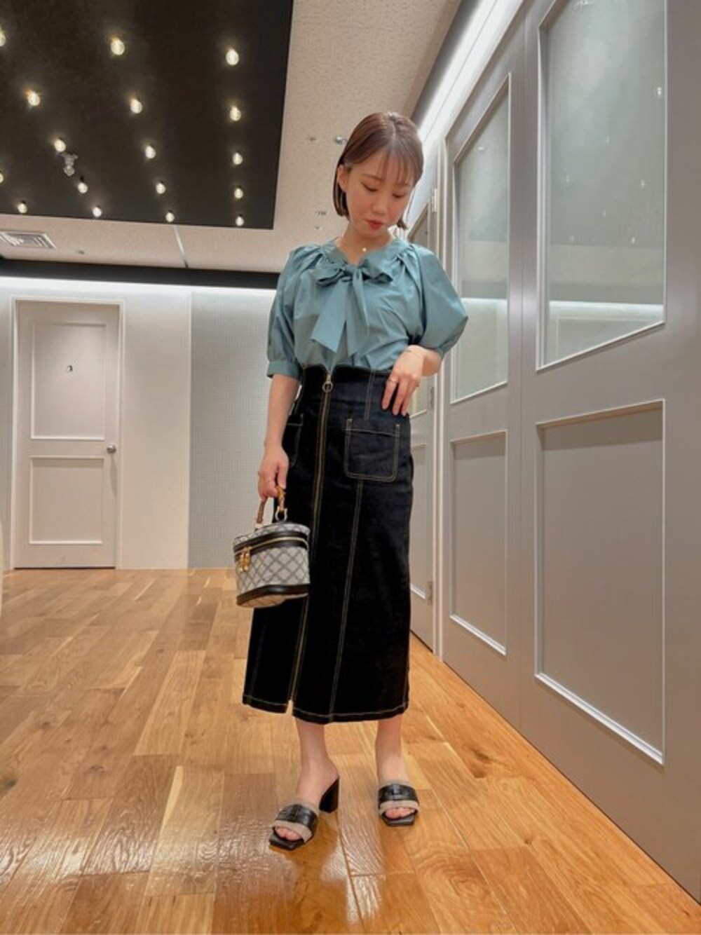 グリーン系のシャツ/ブラウス、ブラック系のスカート、ブラック系のショルダーバッグを着用したレディースの夏コーディネートの1枚目の写真