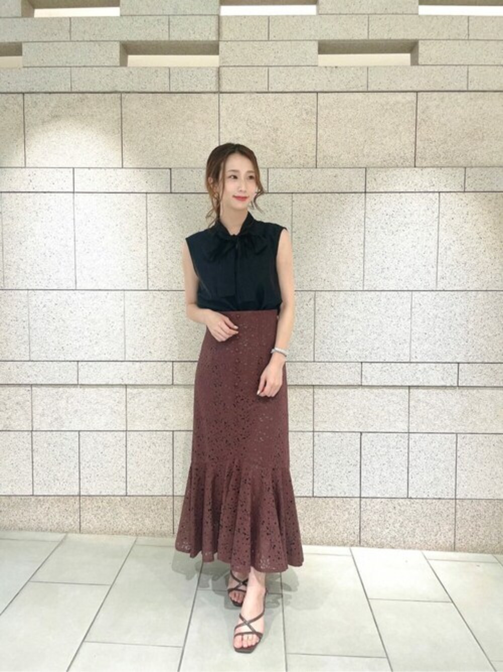 ブラウン系のスカート、ブラック系のシャツ/ブラウスを着用したレディースの夏コーディネートの1枚目の写真