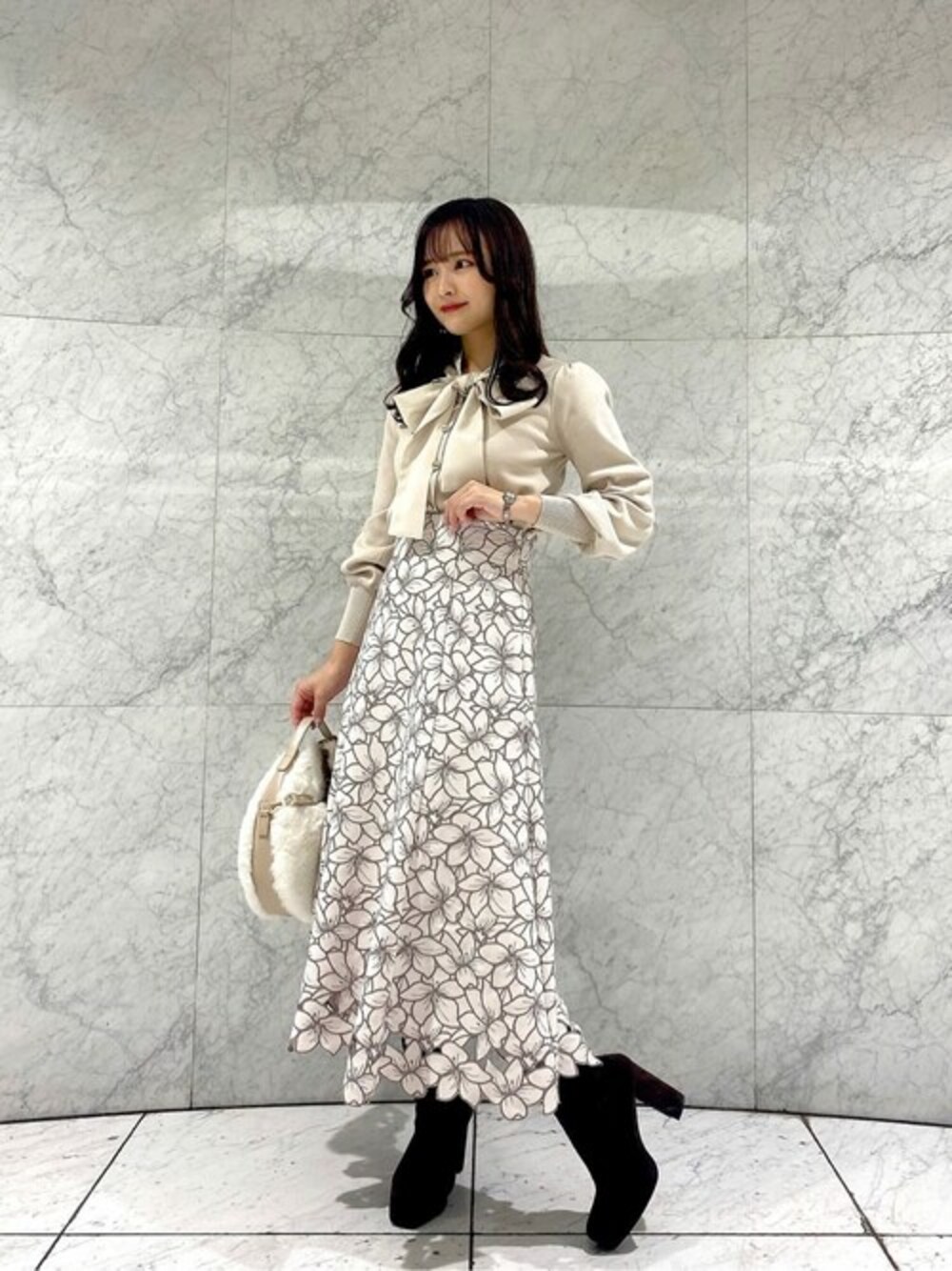 グレー系のスカート、ホワイト系のニット/セーター、ホワイト系のショルダーバッグを着用したレディースの冬コーディネートの1枚目の写真