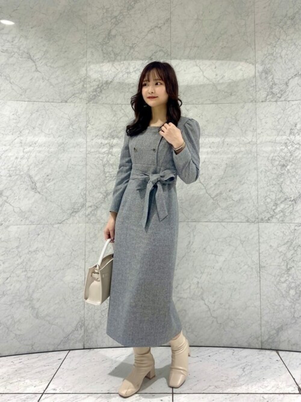 グレー系のワンピース、シルバー系のショルダーバッグを着用したレディースの冬コーディネートの1枚目の写真