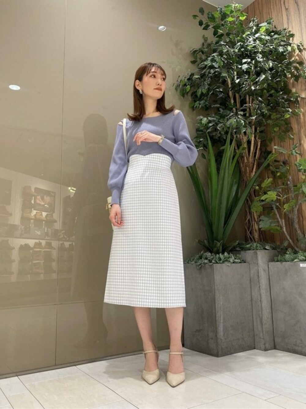 ブルー系のニット/セーター、ブルー系のスカート、ホワイト系のショルダーバッグを着用したレディースの春コーディネートの1枚目の写真