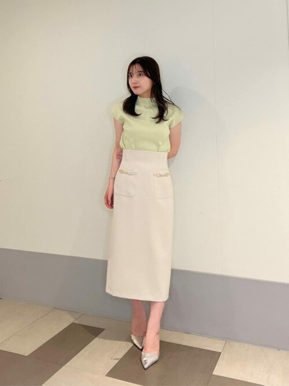 ベージュ系のスカート、グリーン系のニット/セーターを着用したレディースの春コーディネートの1枚目の写真