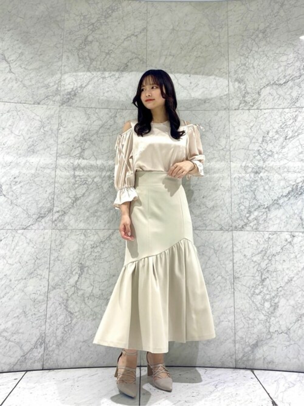 ベージュ系のスカート、ホワイト系のシャツ/ブラウスを着用したレディースの春コーディネートの1枚目の写真