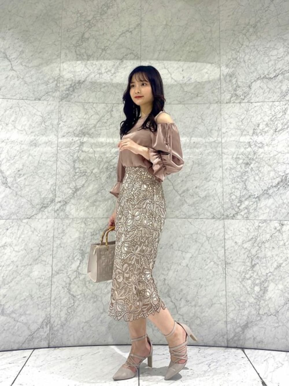 ピンク系のシャツ/ブラウス、ベージュ系のスカート、グレー系のショルダーバッグを着用したレディースの春コーディネートの1枚目の写真