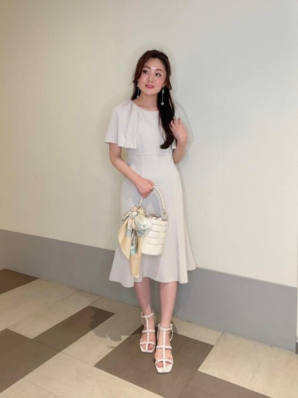 グレー系のワンピース、ホワイト系のハンドバッグ、ホワイト系のパンプスを着用したレディースの夏コーディネートの1枚目の写真