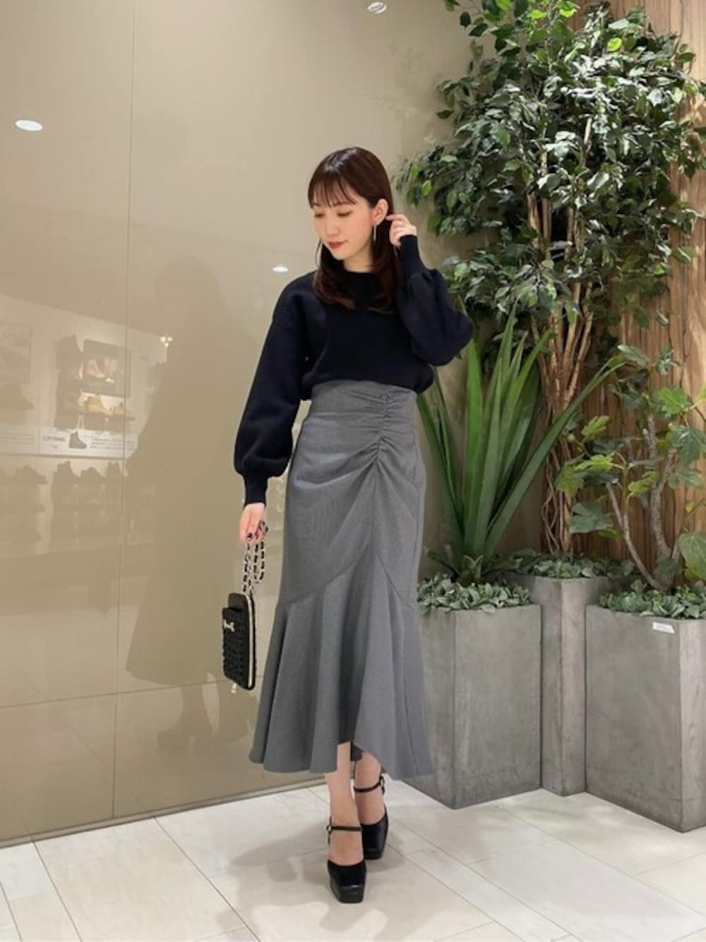 ブラック系のワンピース、グレー系のスカート、ブラック系のスマホグッズを着用したレディースの秋コーディネートの1枚目の写真