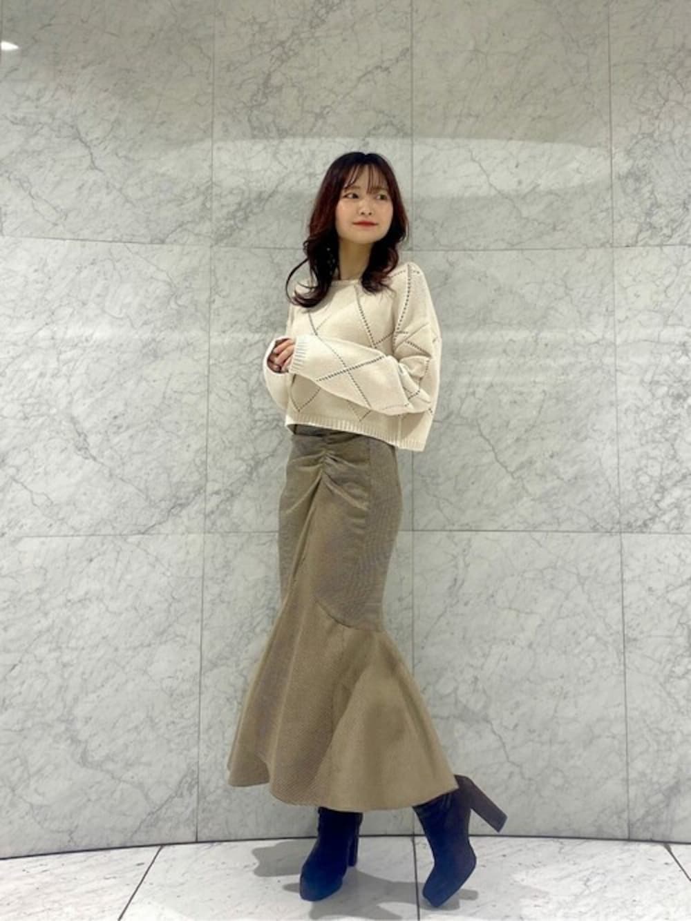 ホワイト系のニット/セーター、ブラウン系のスカート、ブラウン系のブーツを着用したレディースの秋コーディネートの1枚目の写真