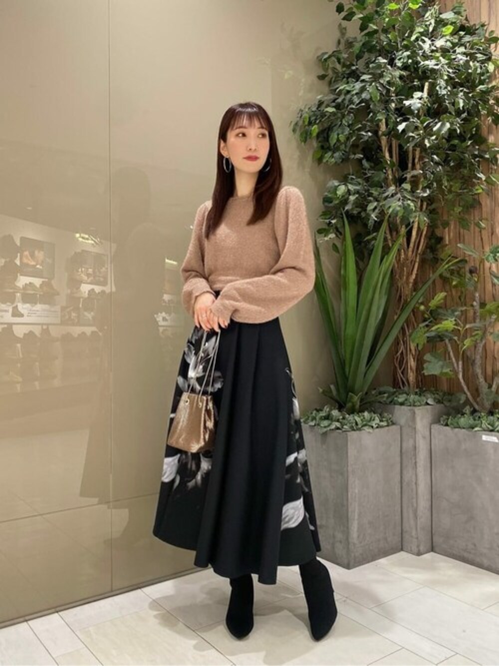 ピンク系のニット/セーター、ブラック系のスカート、ブラウン系のショルダーバッグを着用したレディースの秋コーディネートの1枚目の写真