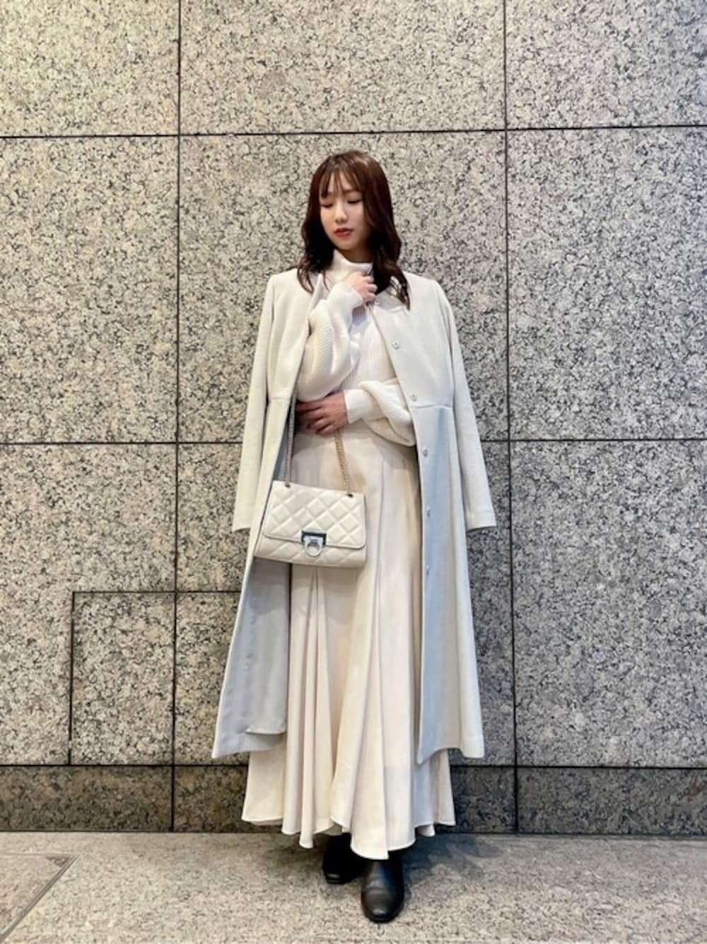 グリーン系のステンカラーコート、ホワイト系のニット/セーター、ホワイト系のスカートを着用したレディースの秋コーディネートの1枚目の写真