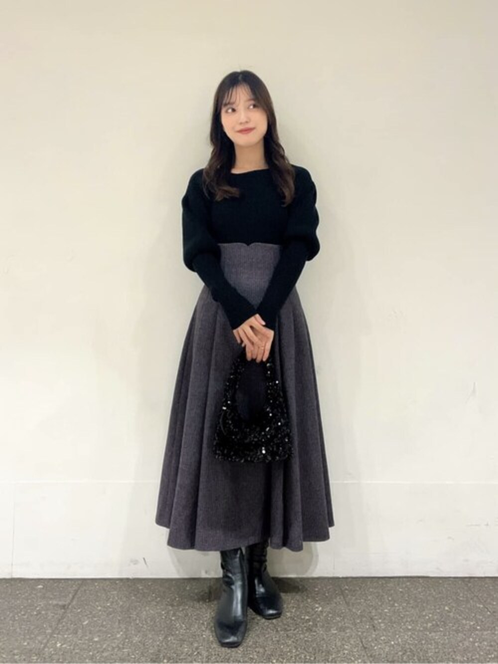 ブラック系のニット/セーター、パープル系のスカート、ブラック系のショルダーバッグを着用したレディースの冬コーディネートの1枚目の写真