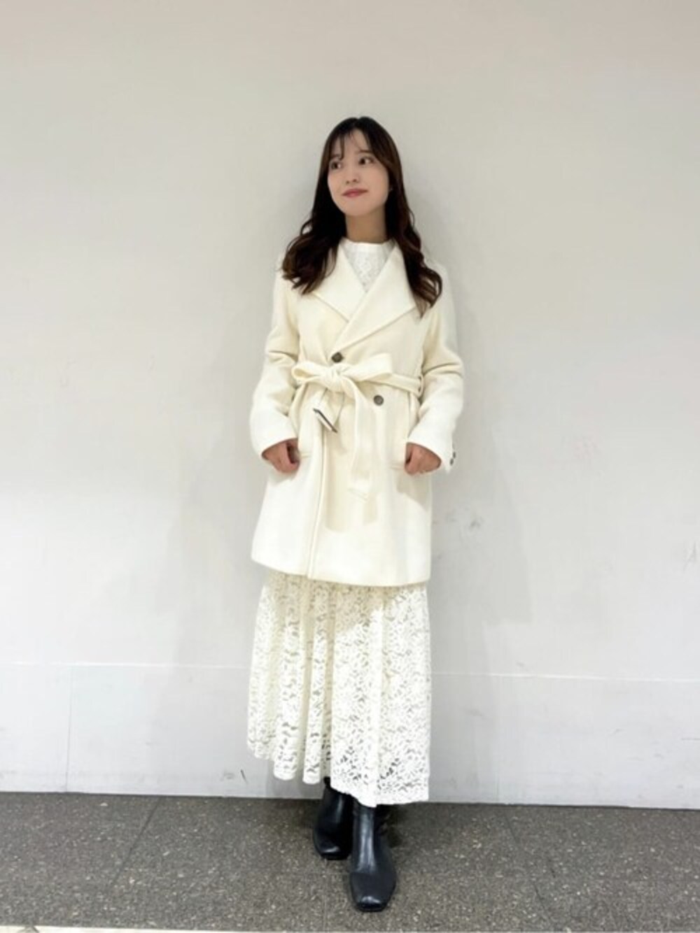 ホワイト系のニット/セーター、ホワイト系のスカート、ホワイト系のステンカラーコートを着用したレディースの冬コーディネートの1枚目の写真