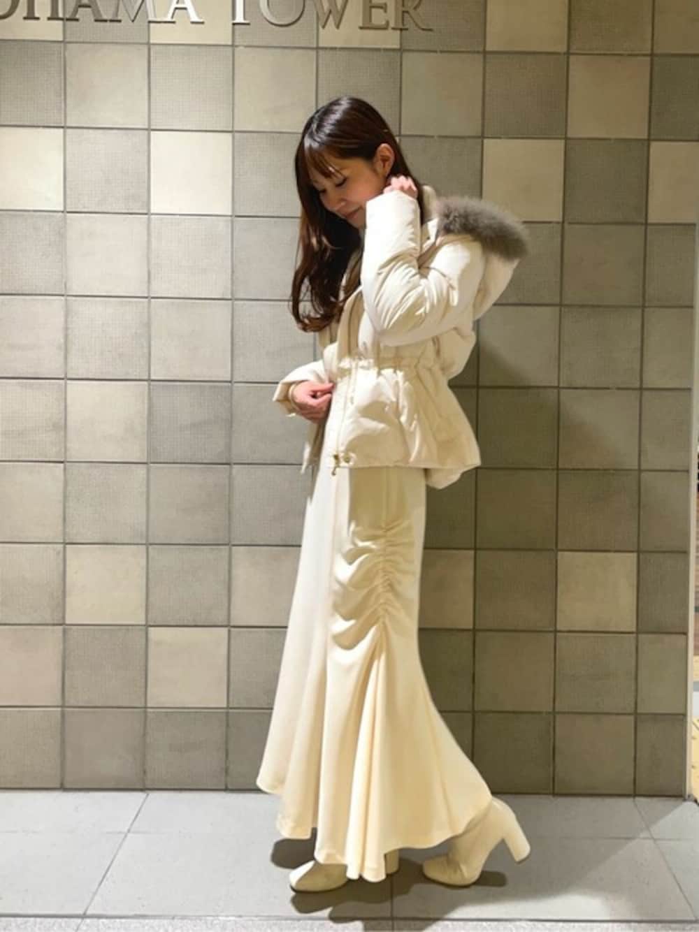 ホワイト系のニット/セーター、ホワイト系のスカート、ホワイト系のダウンジャケット/コートを着用したレディースの冬コーディネートの1枚目の写真