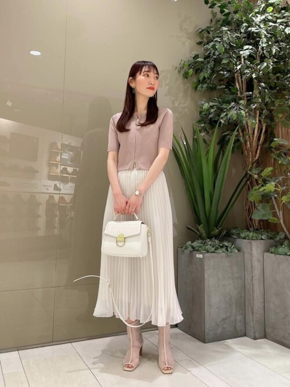 ベージュ系のカーディガン/ボレロ、ホワイト系のスカート、ホワイト系のショルダーバッグを着用したレディースの春コーディネートの1枚目の写真