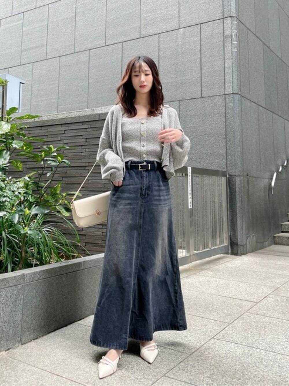 グレー系のニット/セーター、グレー系のワンピース、ブラック系のスカートを着用したレディースの春コーディネートの1枚目の写真