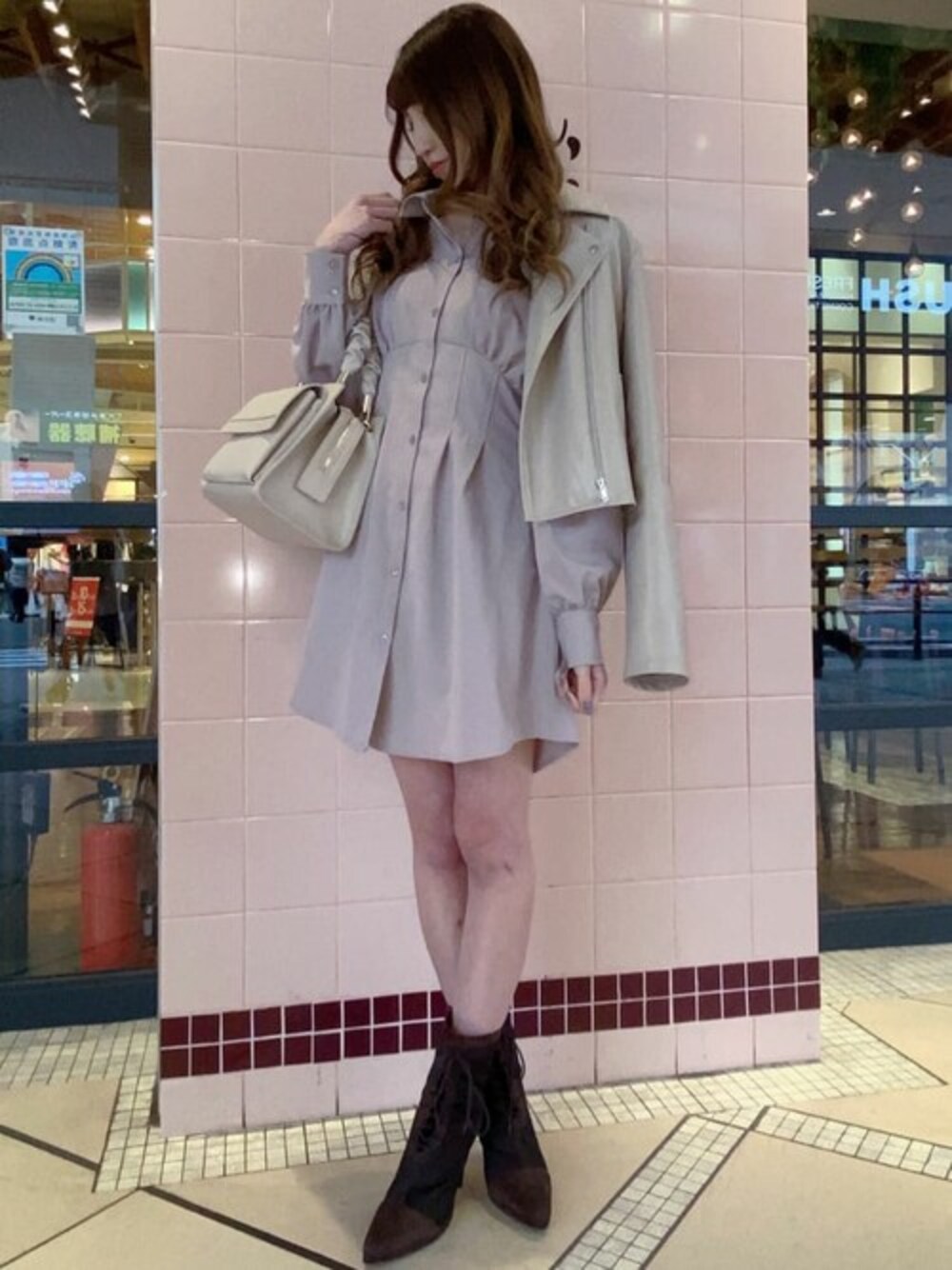 ベージュ系のライダースジャケット、ベージュ系のハンドバッグ、ピンク系のワンピースを着用したレディースの冬コーディネートの1枚目の写真