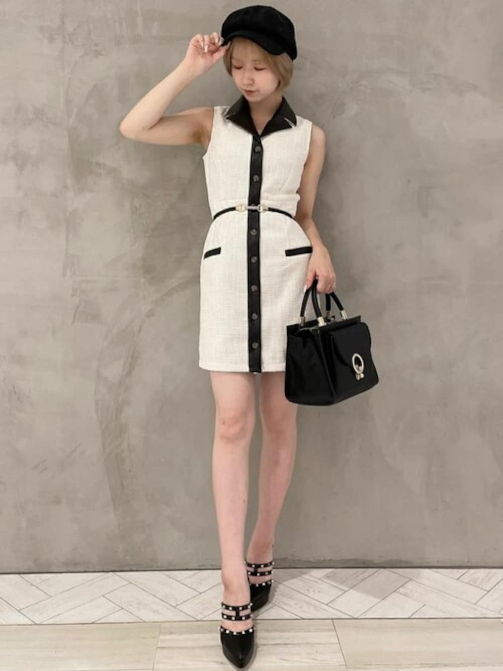 ブラック系のハンドバッグ、ブラック系のパンプス、ホワイト系のワンピースを着用したレディースの夏コーディネートの1枚目の写真