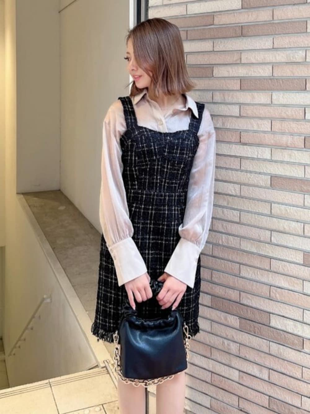 ベージュ系のシャツ/ブラウス、ブラック系のジャンパースカート、ブラック系のハンドバッグを着用したレディースの秋コーディネートの1枚目の写真