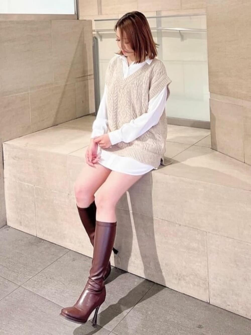 ベージュ系のニット/セーター、ブラウン系のブーツを着用したレディースの秋コーディネートの1枚目の写真