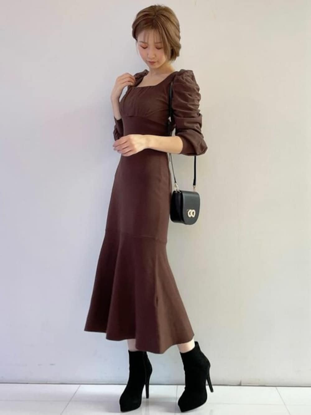 ブラウン系のワンピース、ブラック系のブーツを着用したレディースの秋コーディネートの1枚目の写真