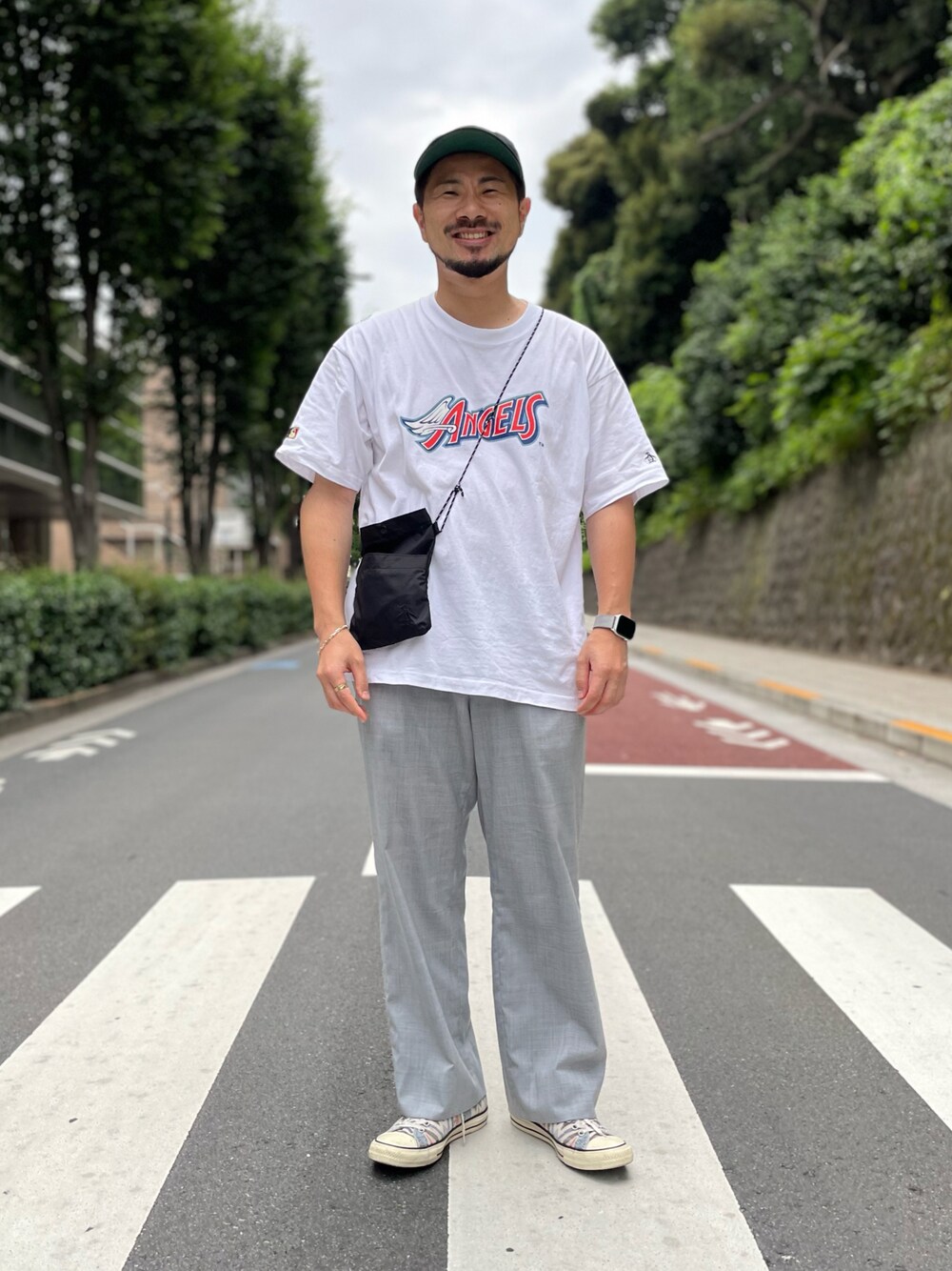 グレー系のスラックス、ホワイト系のTシャツ/カットソー、ブラック系のショルダーバッグを着用したメンズの夏コーディネートの1枚目の写真