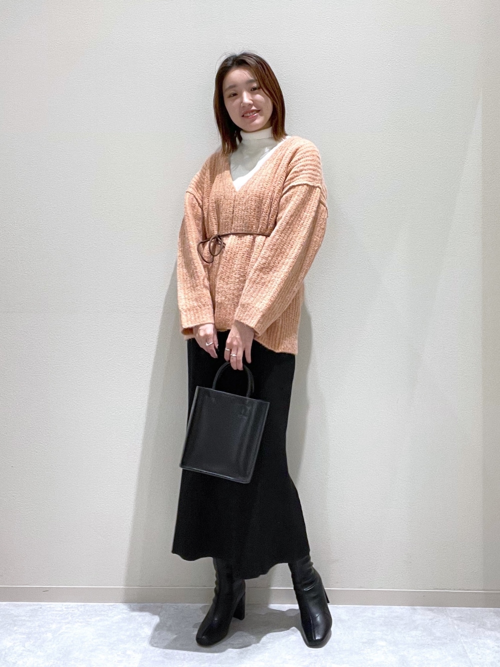 ピンク系のニット/セーター、ブラック系のブーツ、ブラック系のショルダーバッグを着用したレディースの秋コーディネートの1枚目の写真