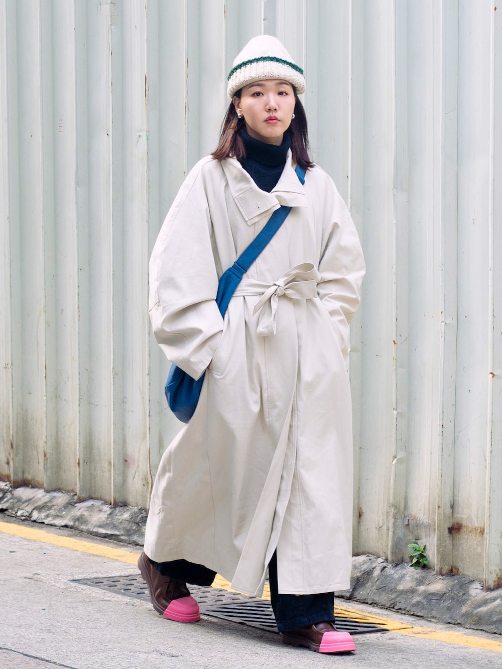 ブラウン系のドレスシューズ、ブルー系のバッグ、ベージュ系のチェスターコートを着用したレディースの冬コーディネートの1枚目の写真