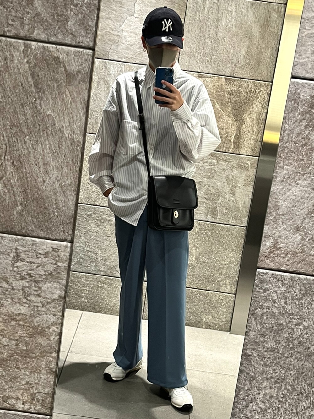 グレー系のスニーカー、ブルー系のスラックス、ブラック系のショルダーバッグを着用したメンズの秋コーディネートの1枚目の写真