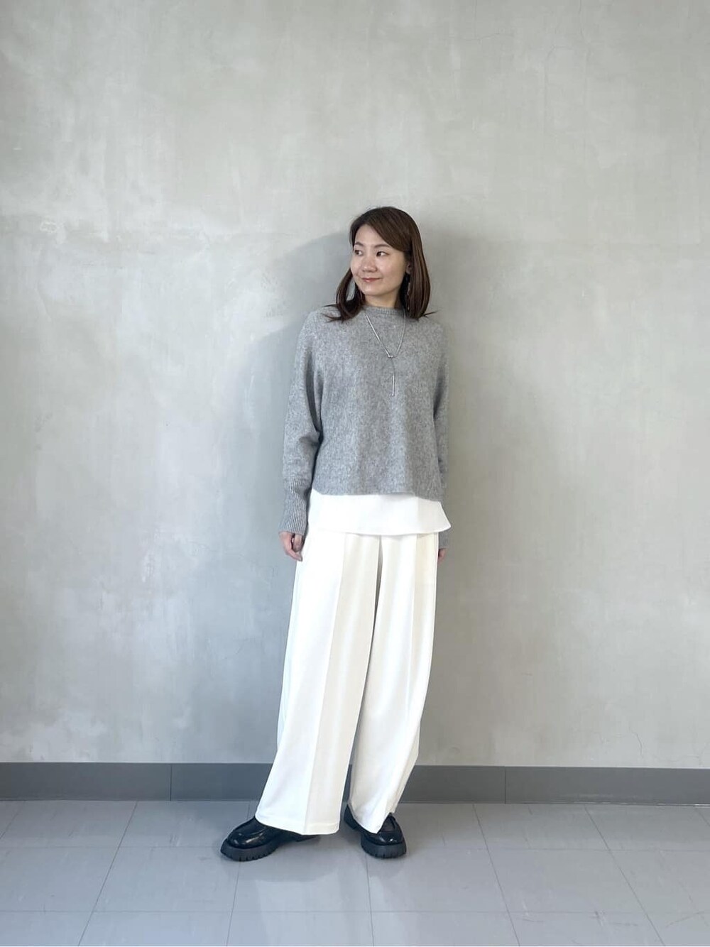 グレー系のニット/セーター、ホワイト系のシャツ/ブラウス、ホワイト系のその他パンツを着用したレディースの秋コーディネートの1枚目の写真