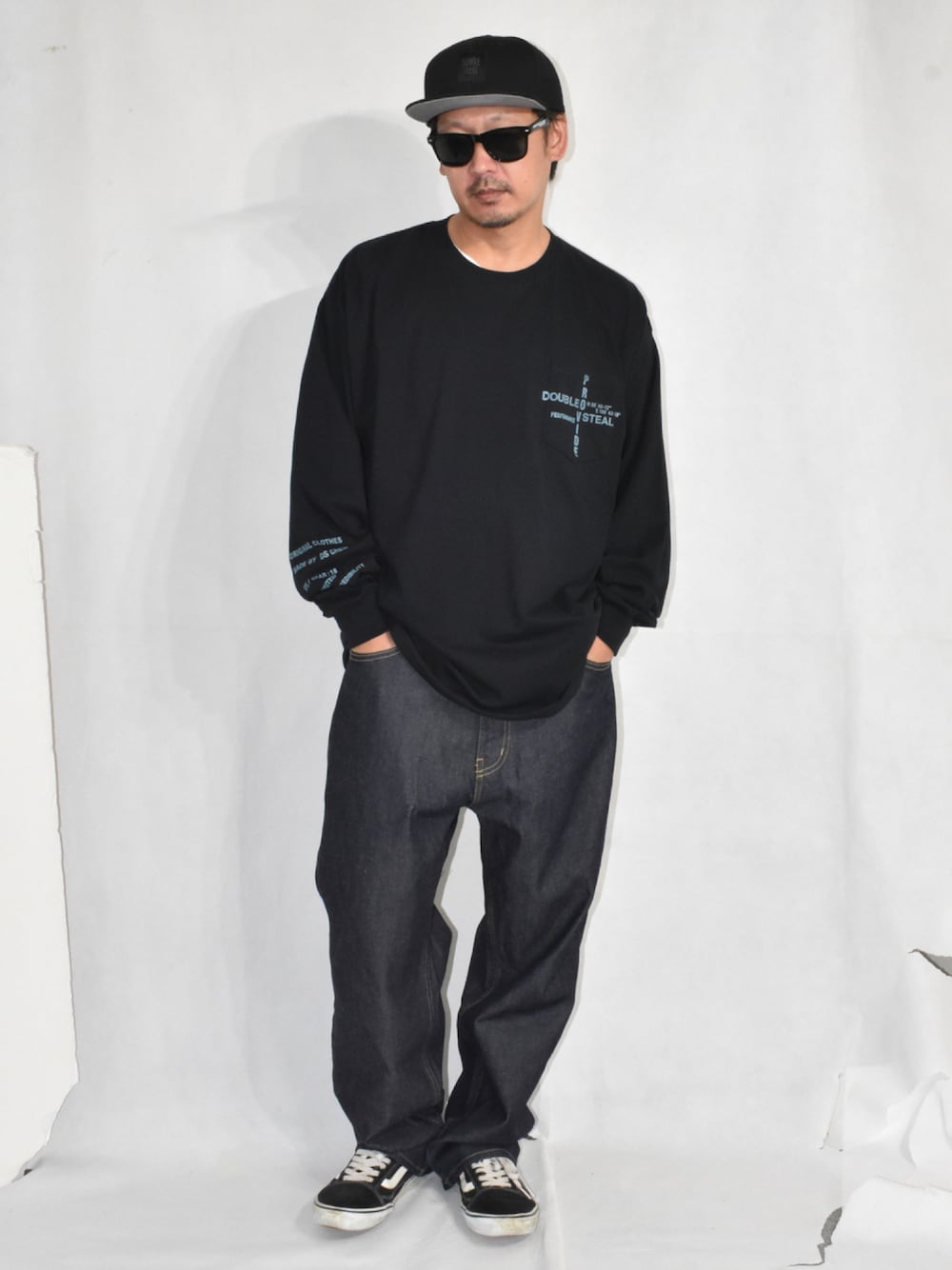 ブラック系のスニーカー、ブルー系のデニムパンツ、ブラック系のTシャツ/カットソーを着用したメンズの秋コーディネートの1枚目の写真