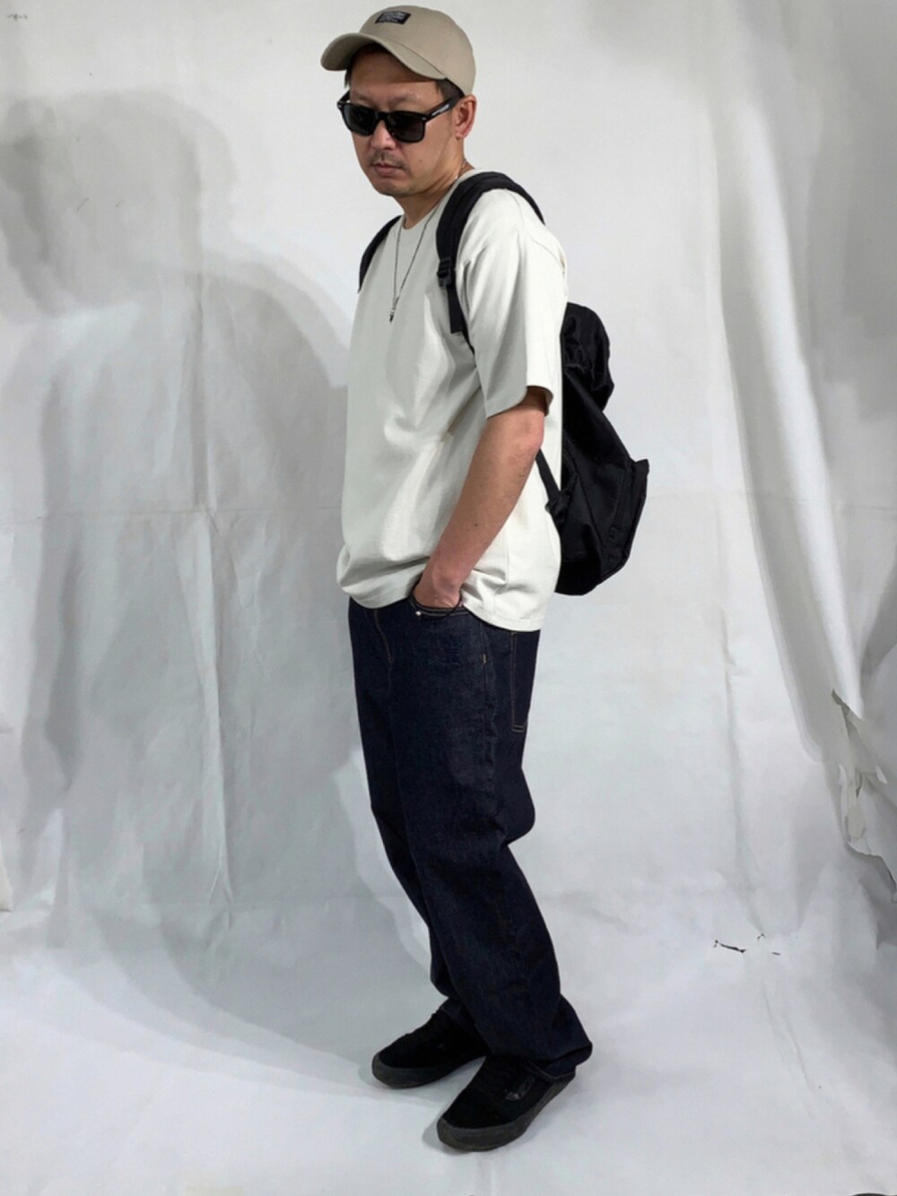 ブラック系のスニーカー、ブルー系のデニムパンツ、ブラック系のバックパック/リュックを着用したメンズの夏コーディネートの1枚目の写真