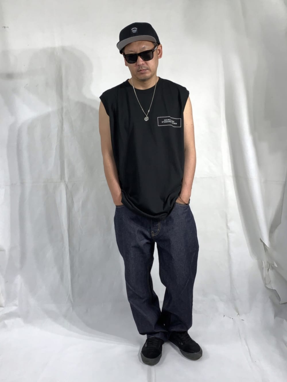 ブラック系のスニーカー、ブルー系のデニムパンツ、ブラック系のタンクトップを着用したメンズの夏コーディネートの1枚目の写真