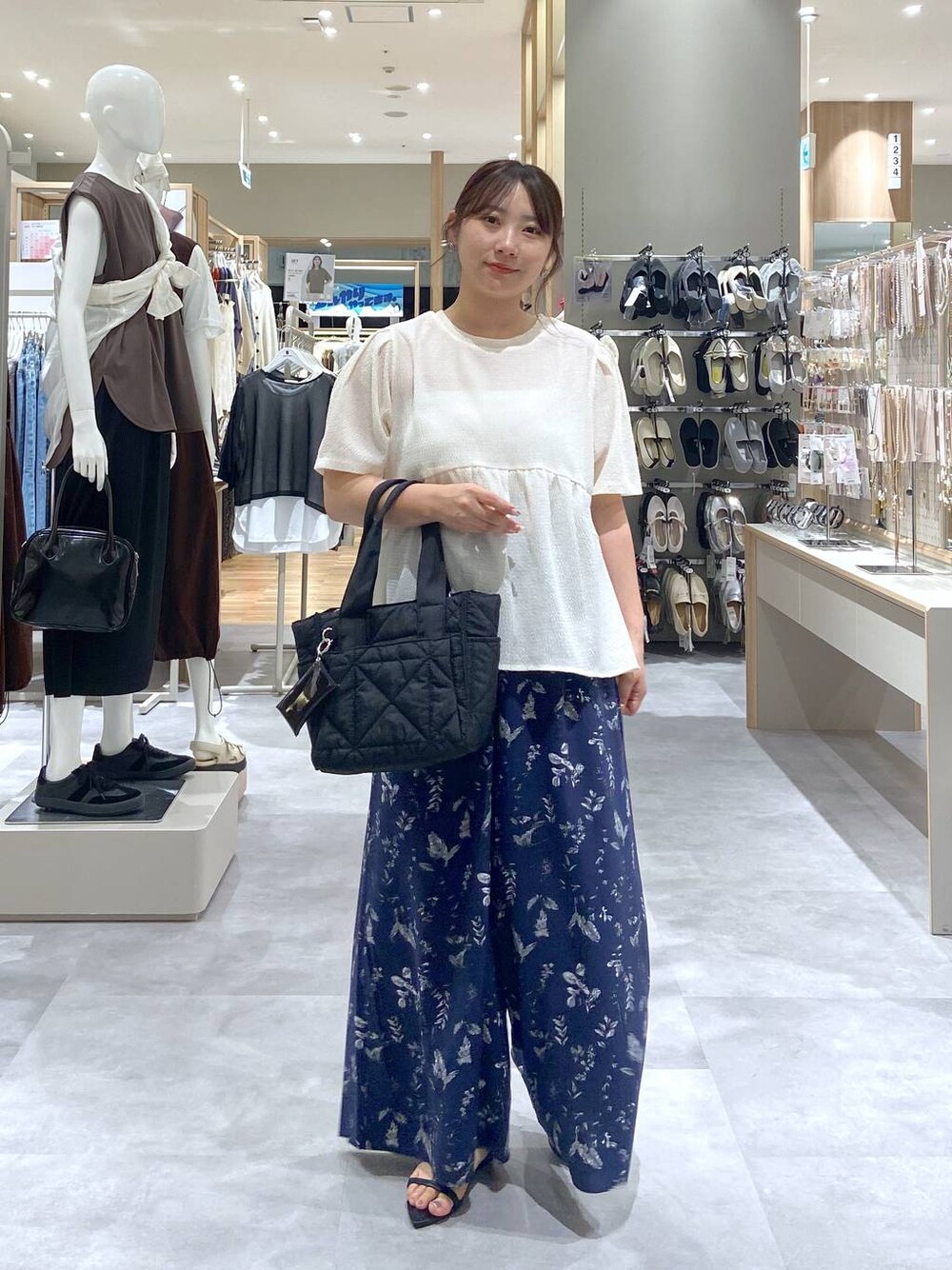 ブラック系のトートバッグ、ベージュ系のTシャツ/カットソー、ブラック系のサンダルを着用したレディースの夏コーディネートの1枚目の写真